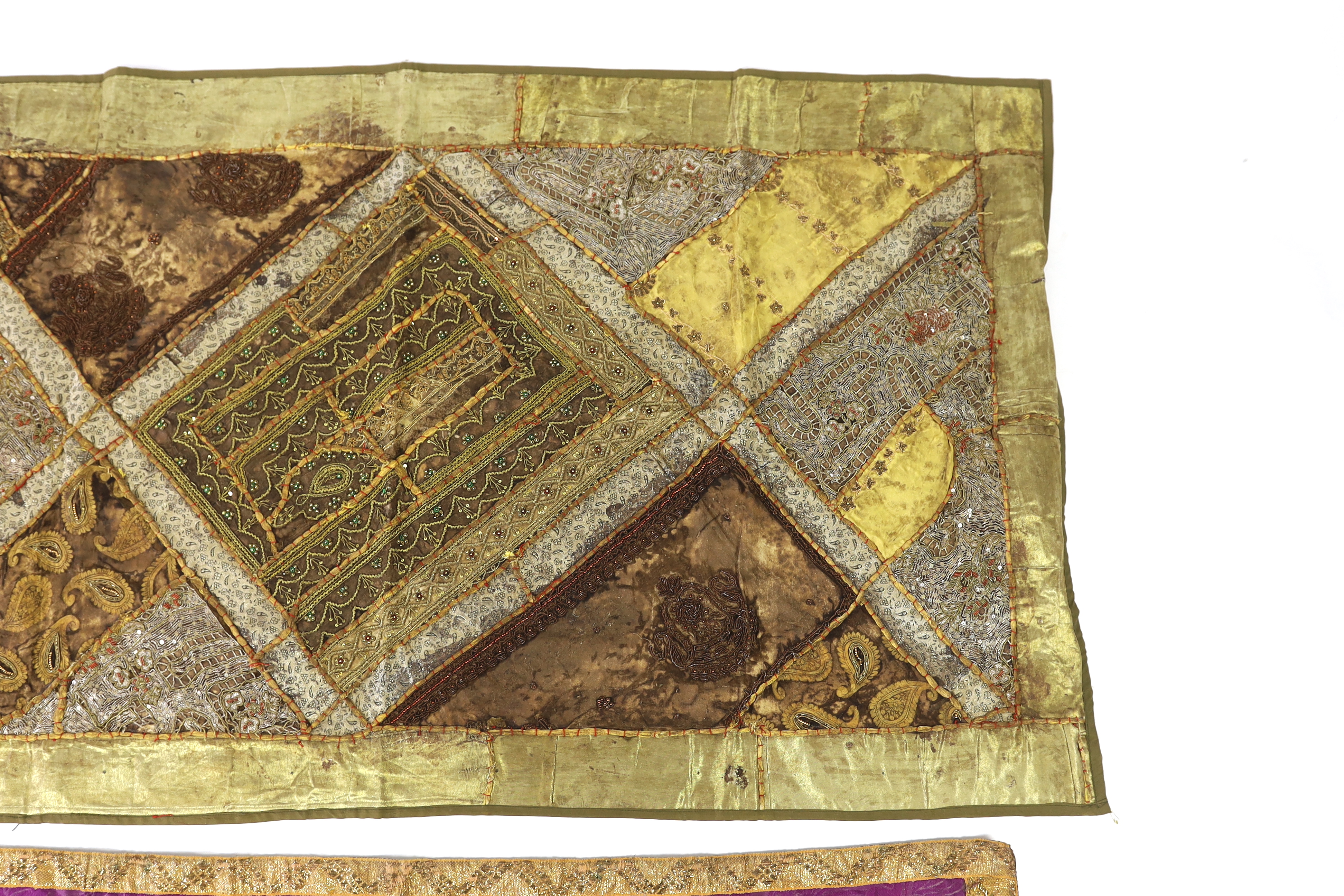 A 20th century Indian patchwork hanging, designed in golds and browns using patchwork batik, beadwork and metallic embroidery, each bordered with thick silk strands bound together, the hanging then bordered with gold met